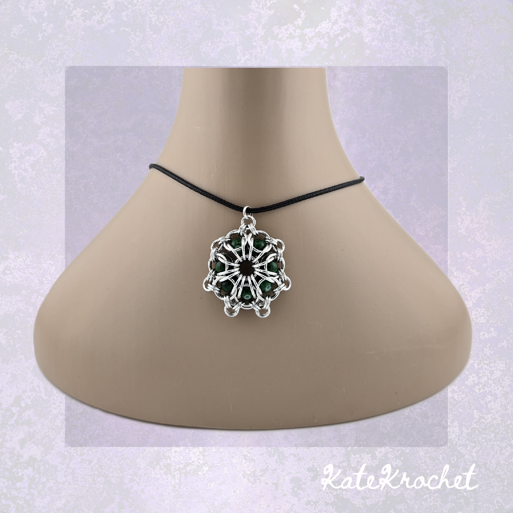 A Chainmaille captured glass bead flower pendant necklace with Dark Green glass beads, displayed on a beige mannequin bust by KateKrochet.