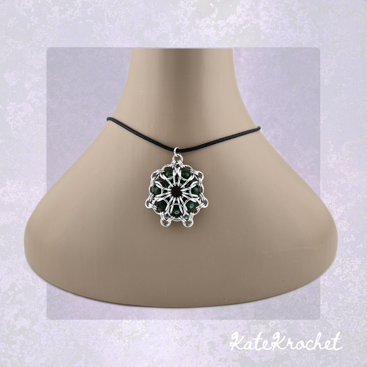 A Chainmaille captured glass bead flower pendant necklace with Dark Green glass beads, displayed on a beige mannequin bust by KateKrochet.