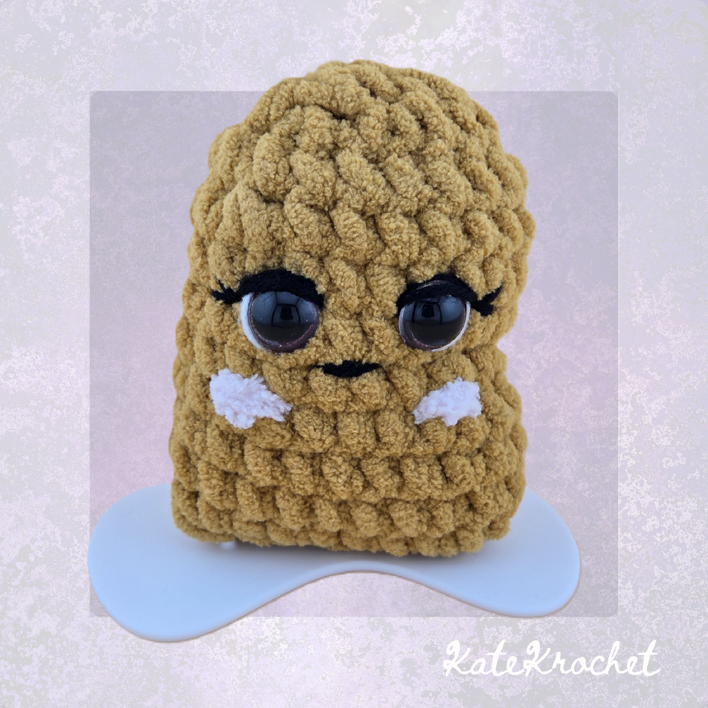 Close-up of handmade Girl Emotional Support Nugget with eyelashes and blush cheeks by KateKrochet